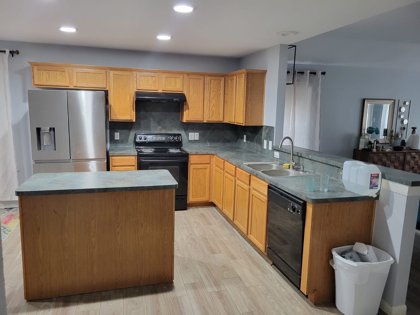 Before: a dated kitchen with oak raised-panel cabinets, worn laminate counters and black appliances.